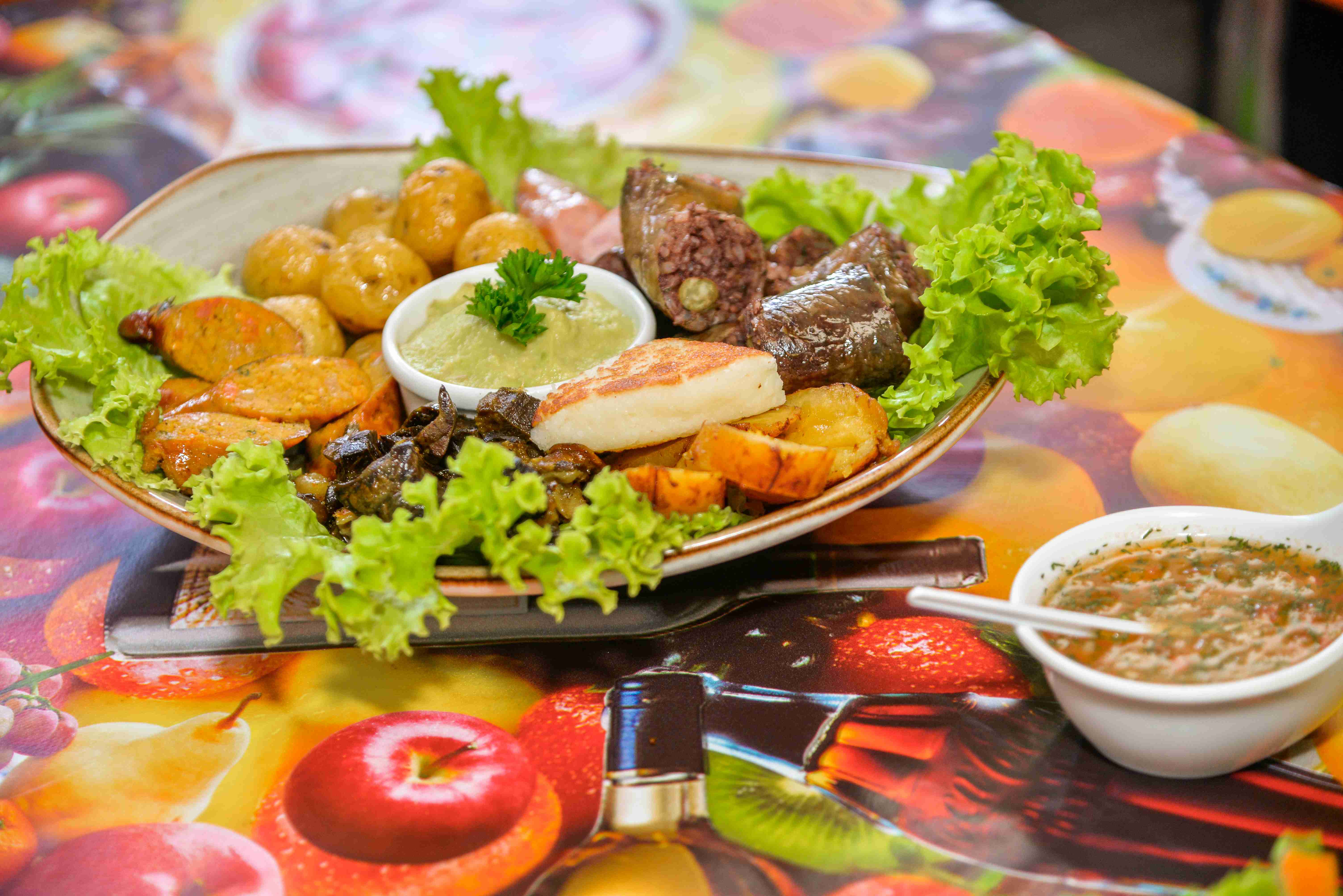 Un plato típico que incluye papa criolla, longaniza, morcilla, chicharrón, queso campesino asado, plátano maduro, lechuga y salsas. Todo dispuesto con equilibrio visual que celebra la cocina casera y la autenticidad colombiana. Foto: Archivo IDT.