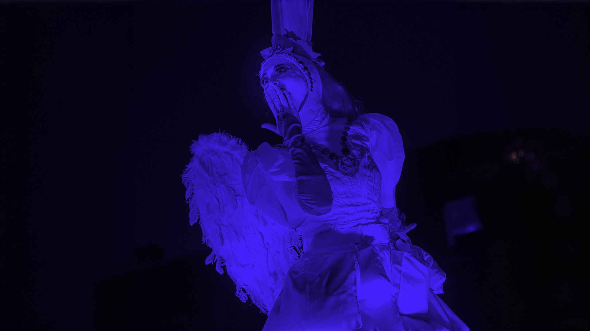 Retrato de intérprete bajo iluminación monocromática azul durante una representación de teatro aéreo contemporáneo. Fotografía Archivo IDT